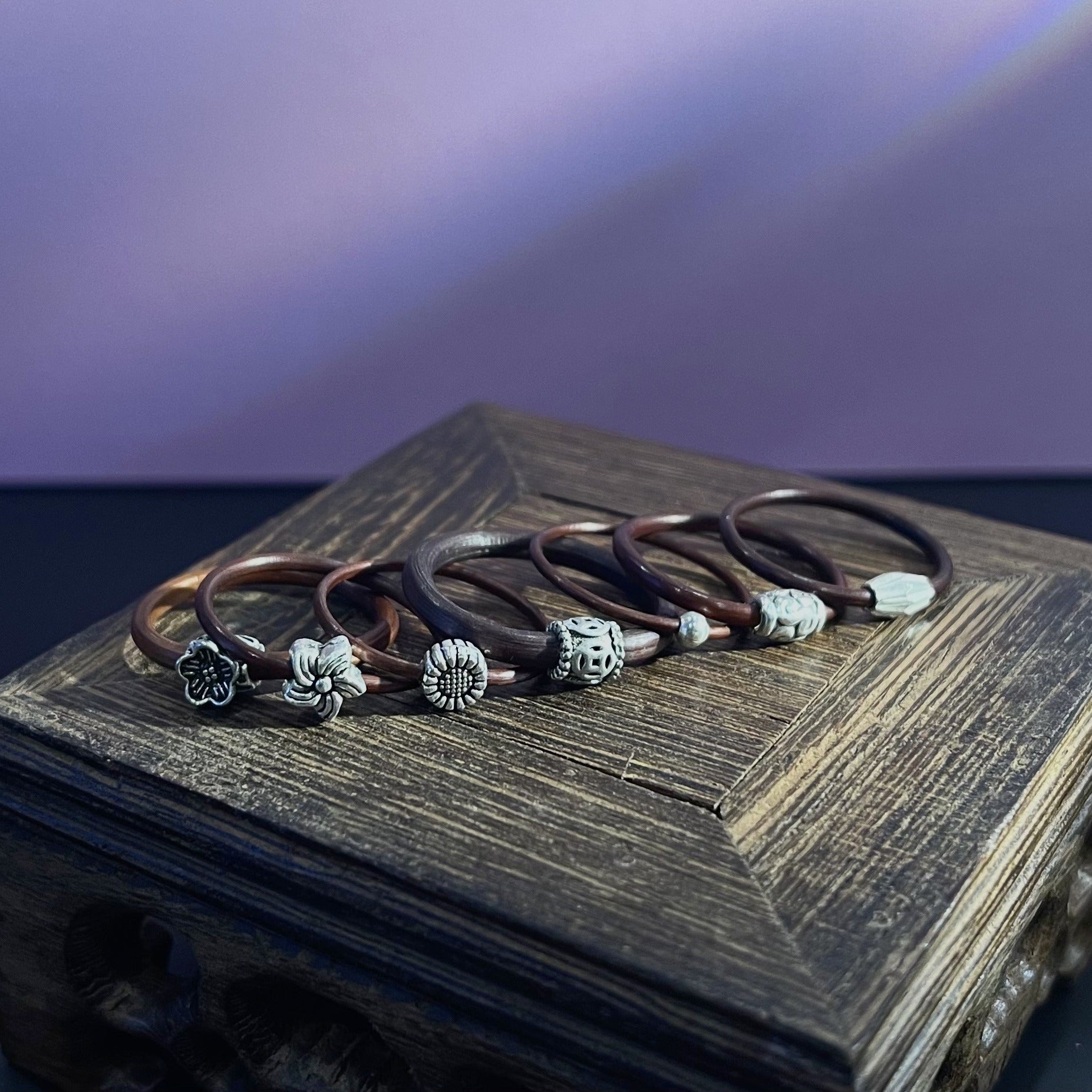 Spatholobus vine rings collection with silver charms on a wooden box